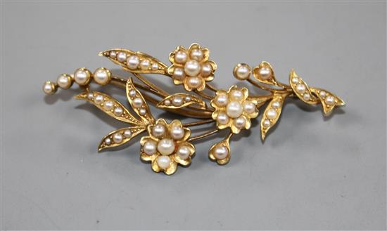 An early 20th century yellow metal and seed pearl set floral spray brooch, 52mm.